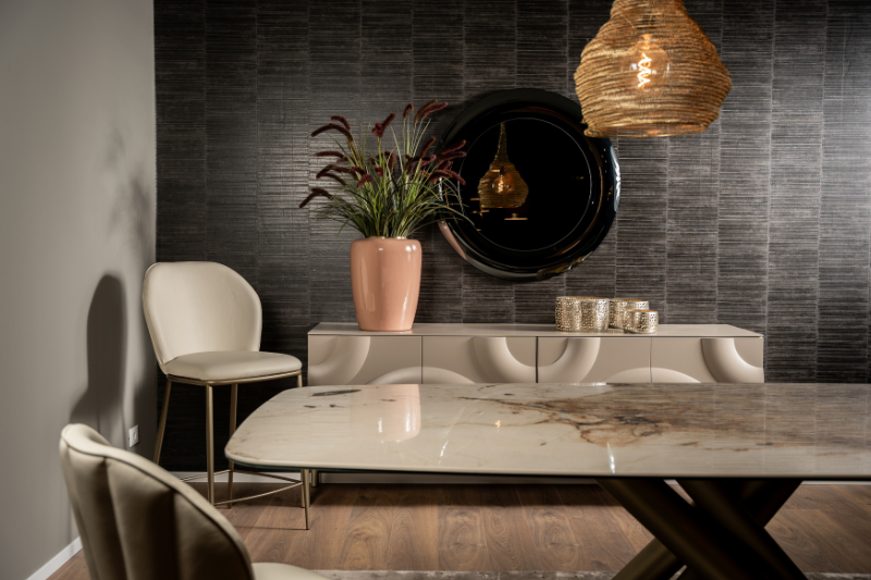 Tavolo allungabile Igor con piano in ceramica effetto marmo e base a gambe incrociate dorate in una zona living