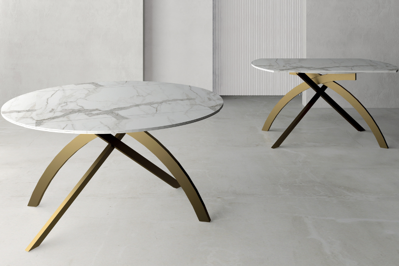 Tavolo rotondo allungabile con piano in marmo e base in metallo oro, con la versione ovale estesa sullo sfondo